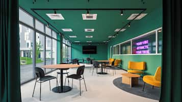 A modern conference room with large windows, a neon sign, and a mix of black and yellow chairs.