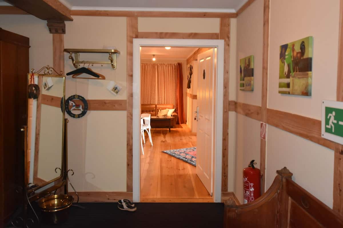 Ein Flur mit Holzboden und einer Tür zu einem Zimmer mit Bett und Fenster.