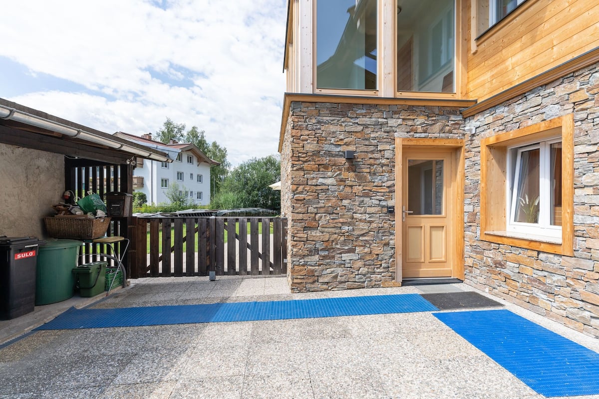 A modern building with a stone facade, a wooden door, and a window with a view of the surrounding area.