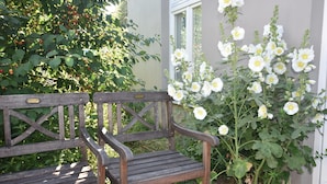 A wooden bench with a metal plaque in front of a flowering plant. - Modern Bungalow in Blowatz Near Sea (Blowatz)