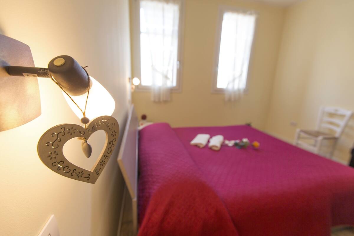 A room with a bed, a heart-shaped decoration, and a lamp.