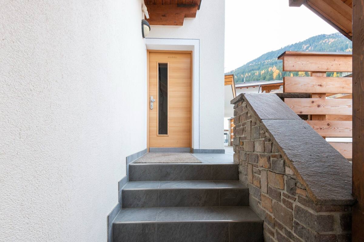 A staircase leading to a wooden door with a small stone wall on the right.