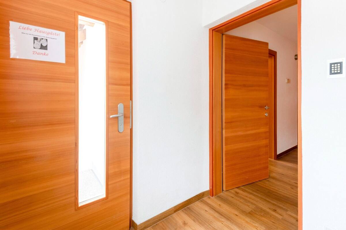 A hallway with wooden doors, one of which has a sign.