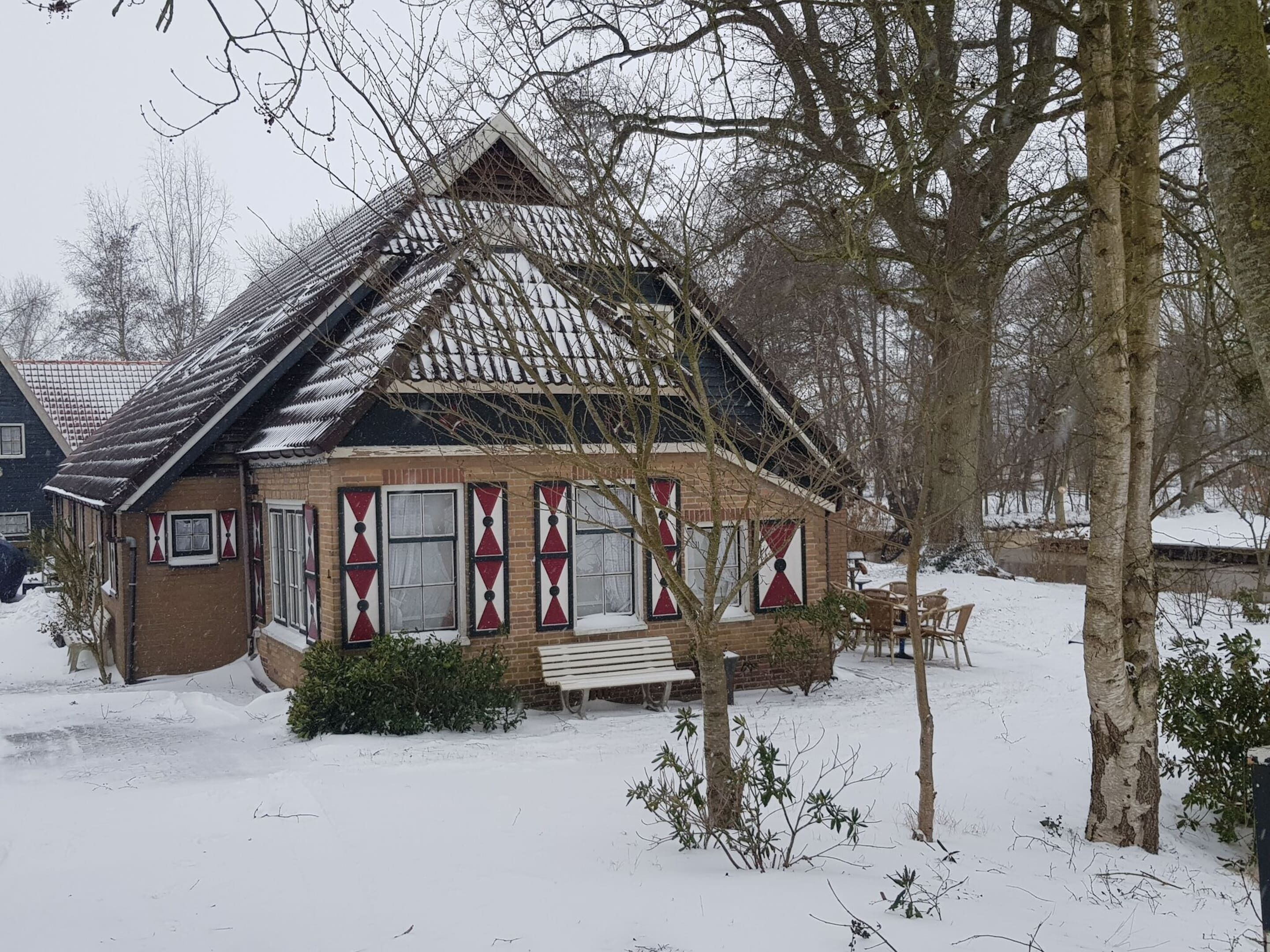 Une maison recouverte de neige, avec un toit en pente et un porche à l’avant.