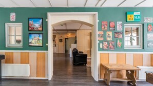 A hallway with a wooden floor, a black leather chair, and a wooden table. - Attractive Farmhouse in Giethoorn With Garden (Giethoorn)