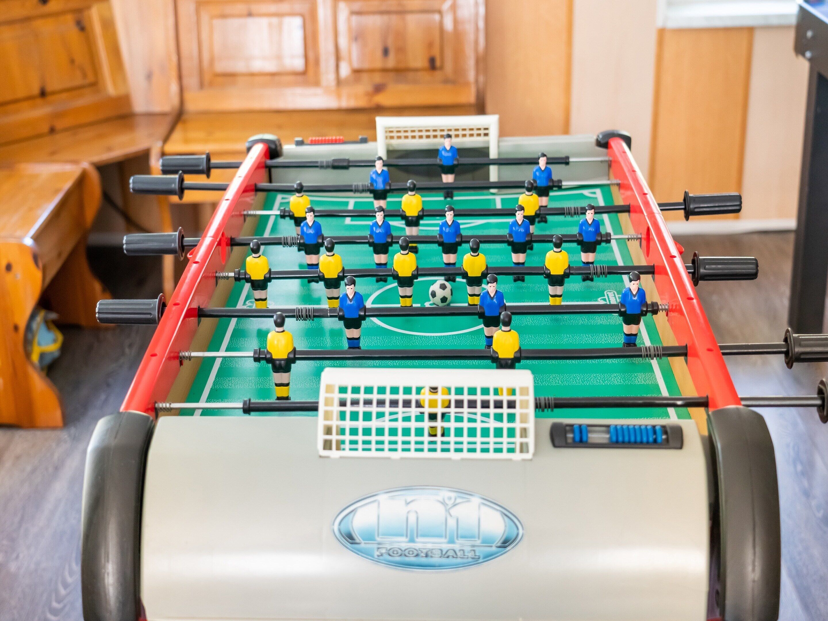 A foosball table with a soccer field layout, including goal areas and player figures.