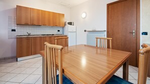 A modern kitchen with wooden cabinets, a built-in microwave, and a dining table with chairs.