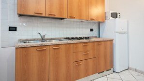 A kitchen with wooden cabinets, a stainless steel sink, a gas stove, and a white refrigerator.