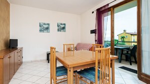 A dining area with a wooden table and chairs, a TV on a cabinet, and artwork on the walls.