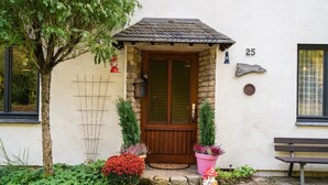 A house with a wooden door, number 25, a bench, and potted plants. - Large, Detached Holiday Home in Willingen With Garden (Willingen)
