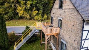 A two-story house with a wooden deck and a yellow staircase leading to a balcony. - Large, Detached Holiday Home in Willingen With Garden (Willingen)