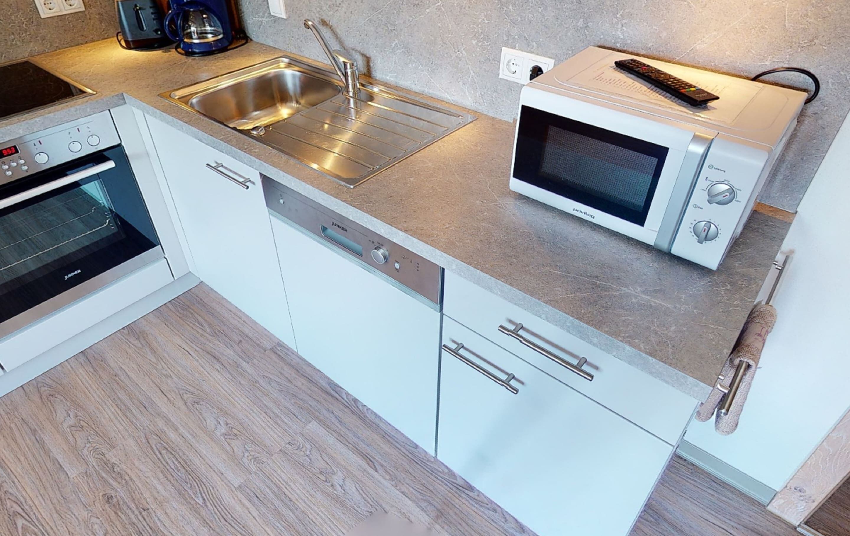 Uma cozinha compacta com forno embutido, micro-ondas e pia.