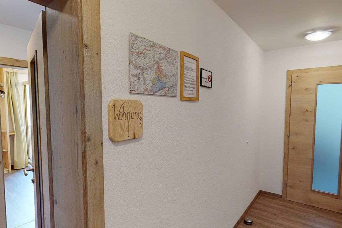 Un pasillo con una puerta de madera, un mapa y un cartel de bienvenida en la pared.