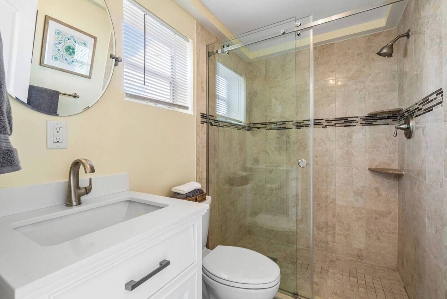 A bathroom with a glass-enclosed shower, a white sink, and a toilet.