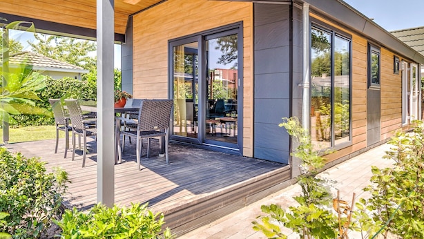 A modern house with a covered patio, large sliding glass doors, and a wooden deck. - Lovely Holiday Home in Kaatsheuvel With Bubble Bath (Kaatsheuvel)