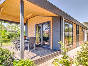 A modern house with a covered patio, large sliding glass doors, and a wooden deck. - Lovely Holiday Home in Kaatsheuvel With Bubble Bath (Kaatsheuvel)