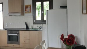 A kitchen with a stove, oven, sink, and cabinets. There is a window with a view of greenery outside. - Cozy Villa With Pool and Parasol in Kirianna (Rethymno)