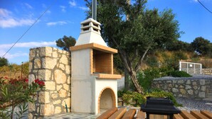 A stone structure with a chimney, surrounded by a garden with pebbles and plants. - Cozy Villa With Pool and Parasol in Kirianna (Rethymno)