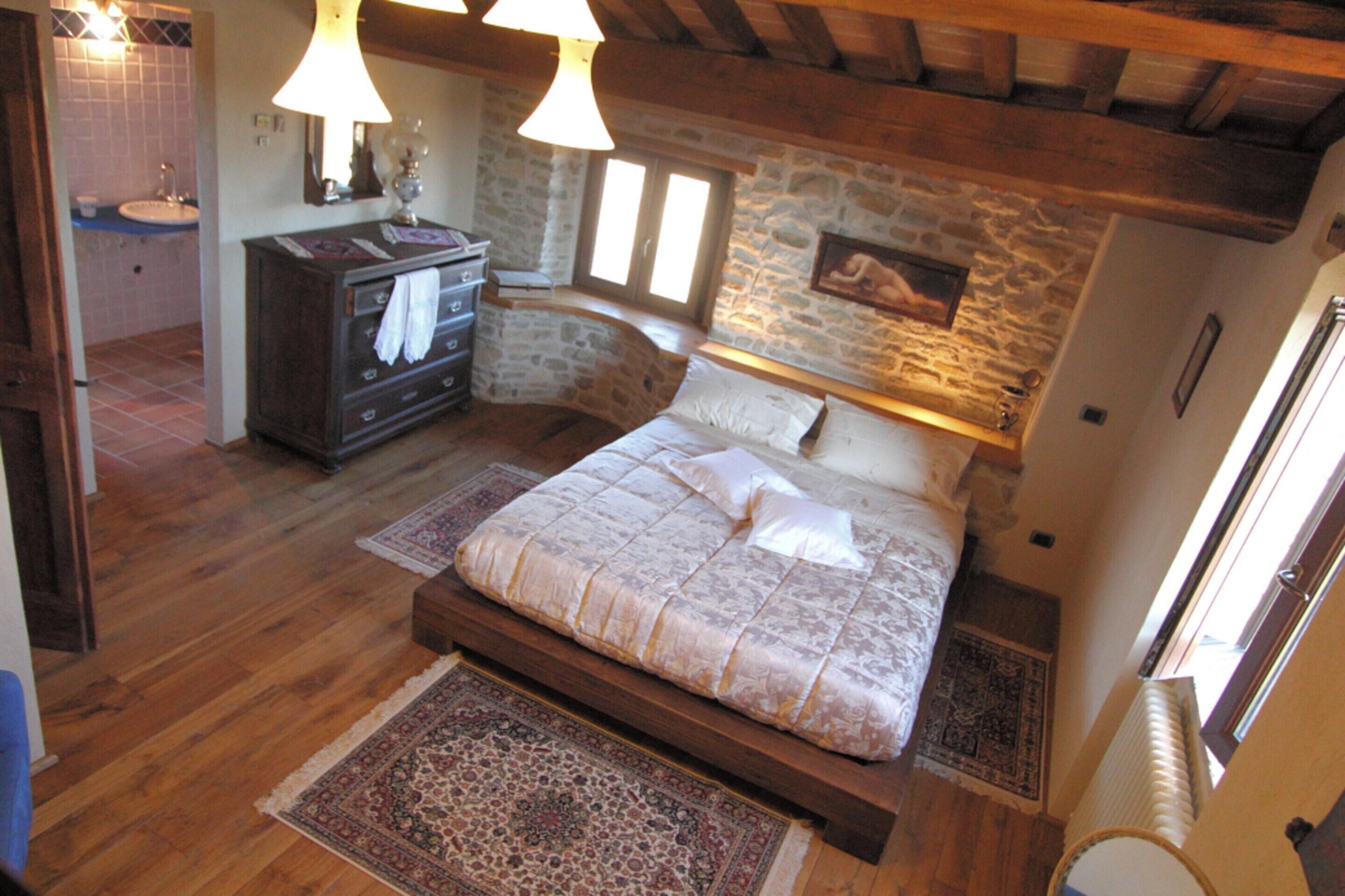 A bedroom with a wooden bed, a stone wall, a nightstand, and a dresser.