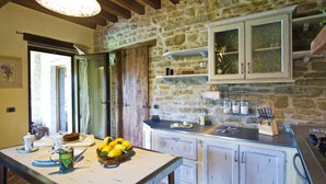 A rustic kitchen with stone walls, wooden beams, and white cabinetry. - Nice Apartment in Apecchio With Shared Swimming Pool (Apecchio)