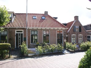 A traditional brick building with a tiled roof, a front entrance, and a signboard. - Fantastic Luxury Vacation Home and Next to the Wadden Sea (Paesens)
