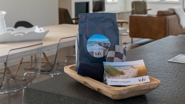 Una bandeja de madera con una postal de temática playera y una bolsa sobre una superficie rugosa.