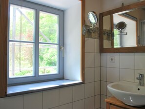 A bathroom with a window, a sink, and a mirror. - Chic Apartment in Thuringia With Sauna (Heringen)