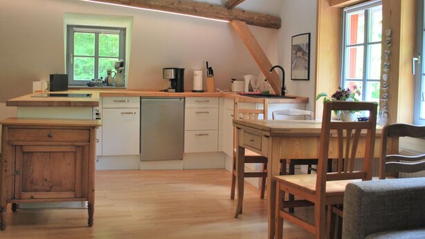 A kitchen with wooden beams, a window, and a dining area with chairs. - Chic Apartment in Thuringia With Sauna (Heringen)