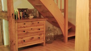A wooden staircase leading to an upper level, a wooden dresser with drawers, and a clear glass vase on the floor. - Chic Apartment in Thuringia With Sauna (Heringen)