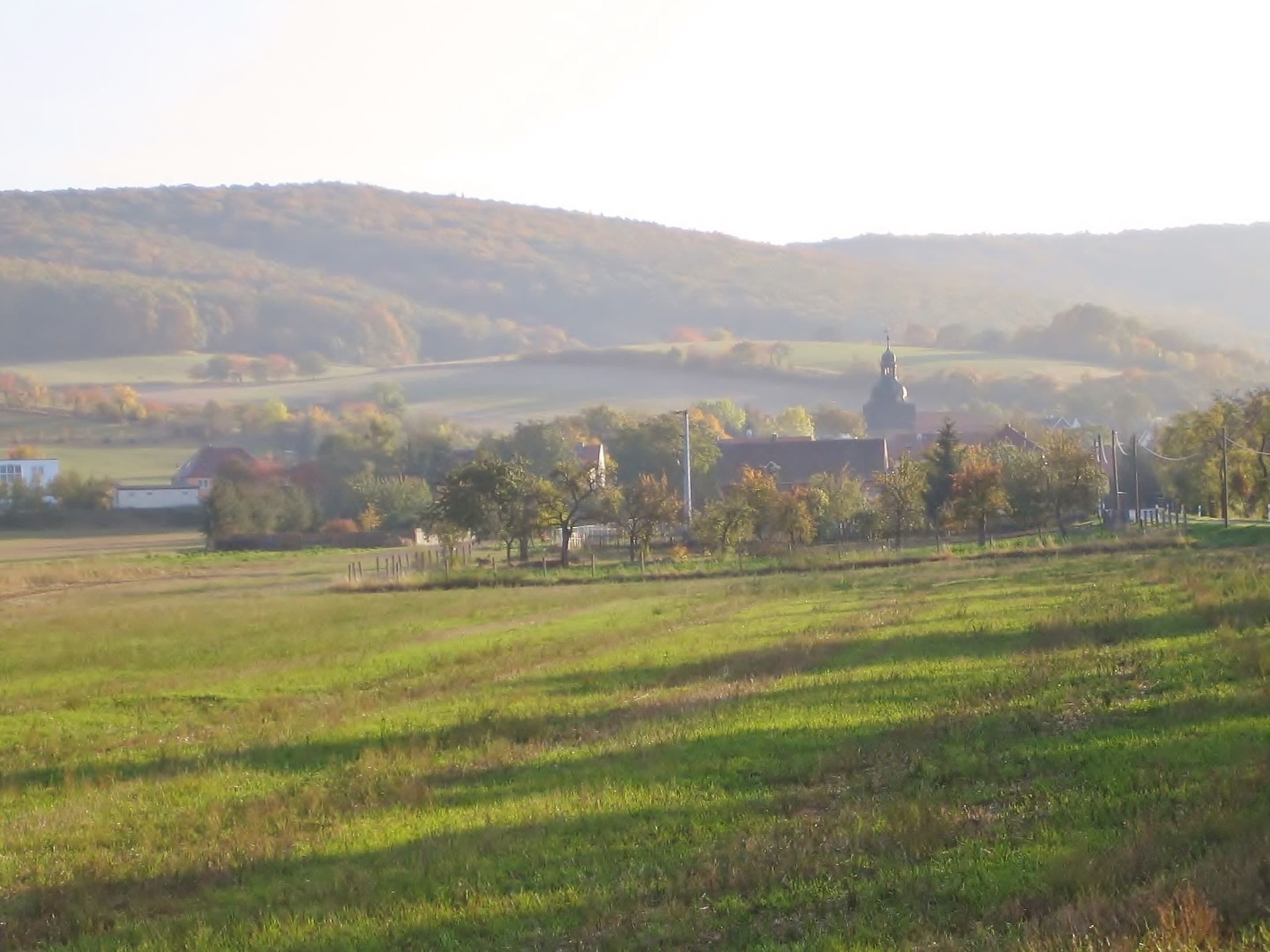 A rural landscape with a church and open fields.