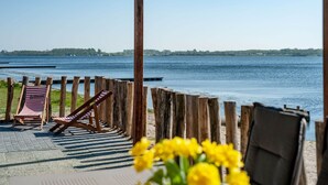 A wooden deck with two striped lounge chairs facing a calm body of water. - Exclusive Apartment on the Ground Floor Directly Located on the Water (Kamperland)