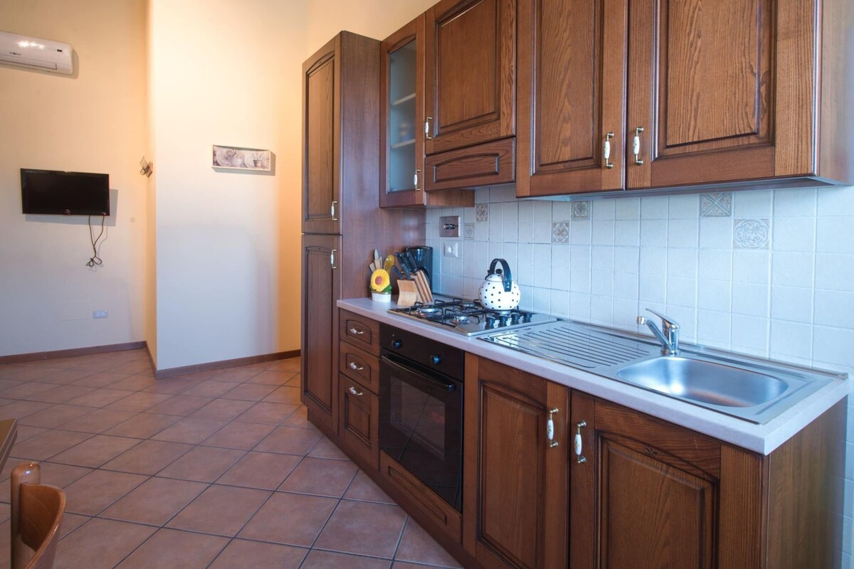 A kitchen with wooden cabinets, a stove, a sink, and a tiled backsplash.