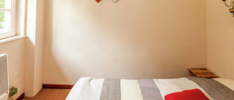 A bedroom with a bed, a radiator, and two wall-mounted artworks.