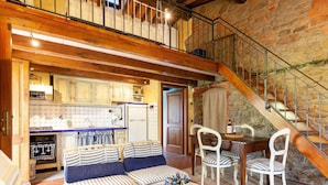 A cozy living area with a sofa, chairs, a table, and a kitchen in the background. - Lovely Farmhouse in Pian di Sco With Barbecue (Castelfranco Piandisco)