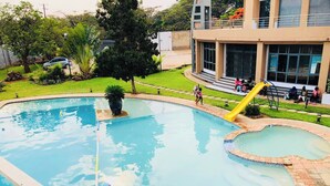 A swimming pool with a slide and a small water feature. - T3C GARDENS (Lusaka)