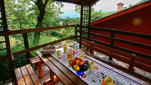 A wooden deck with a table set for breakfast, overlooking a lush green landscape. - Spacious Villa With Pool in Fabriano Italy (Fabriano)