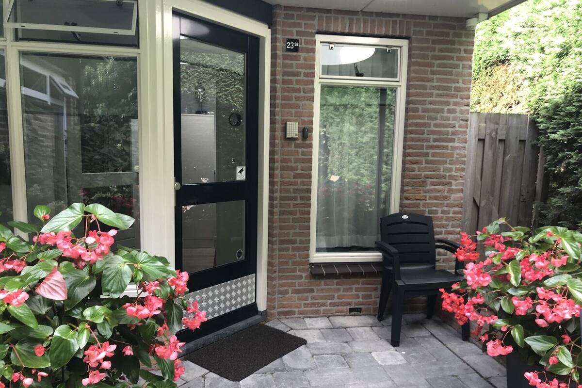 A brick exterior with a black door, a window, and a black chair outside.