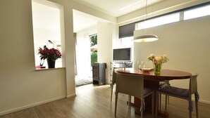 Een moderne eetruimte met een houten tafel, stoelen en een bloemenvaas.