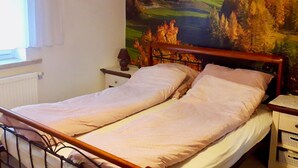 Una cama individual con cabecera de madera en una habitación con un mural de paisaje montañoso.