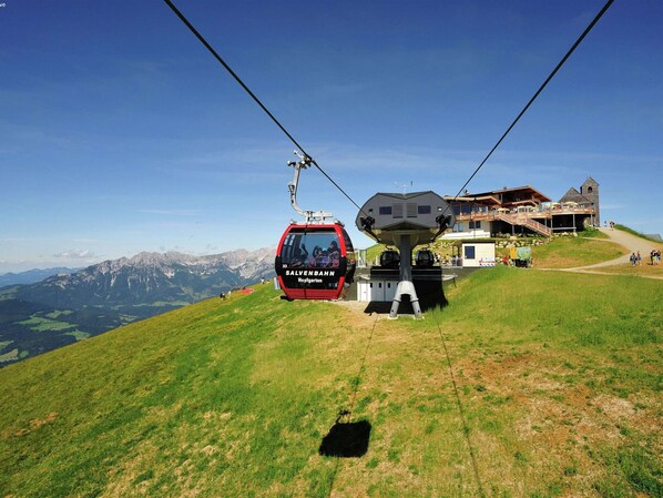 Un teleférico en una estación de montaña con vistas a los Alpes al fondo.