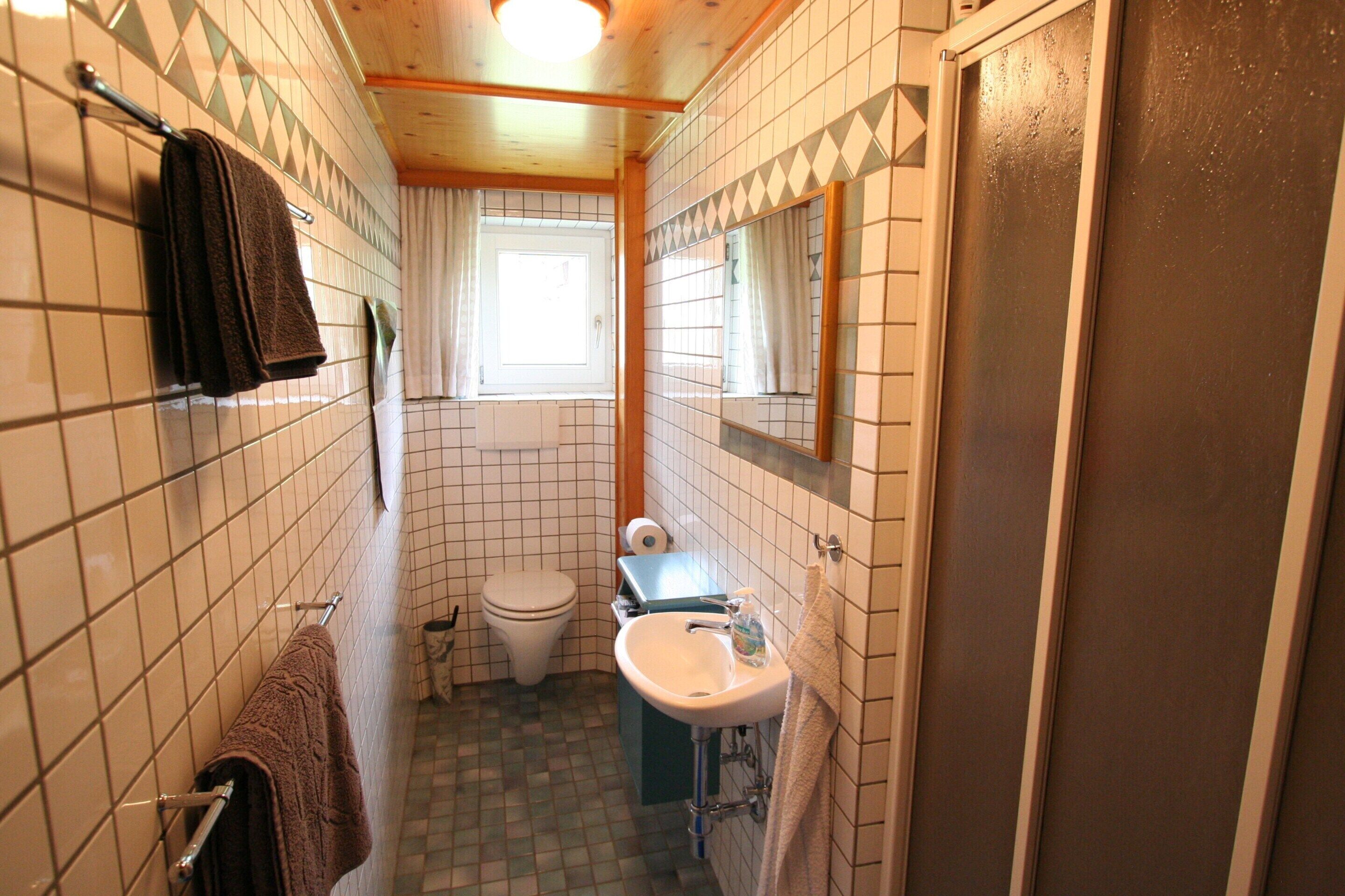 Ein schmales Badezimmer mit Toilette, Waschbecken und Handtuchhalter.