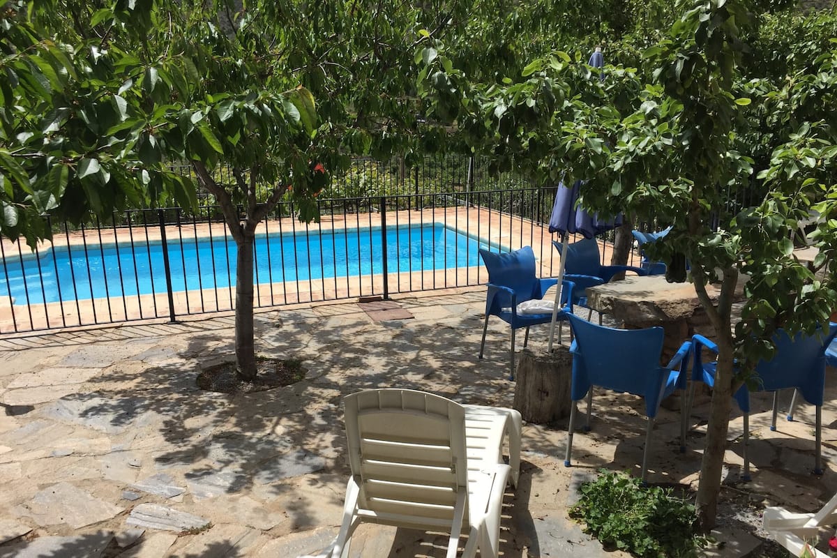 A pool area with a stone patio, blue chairs, and a white lounge chair.
