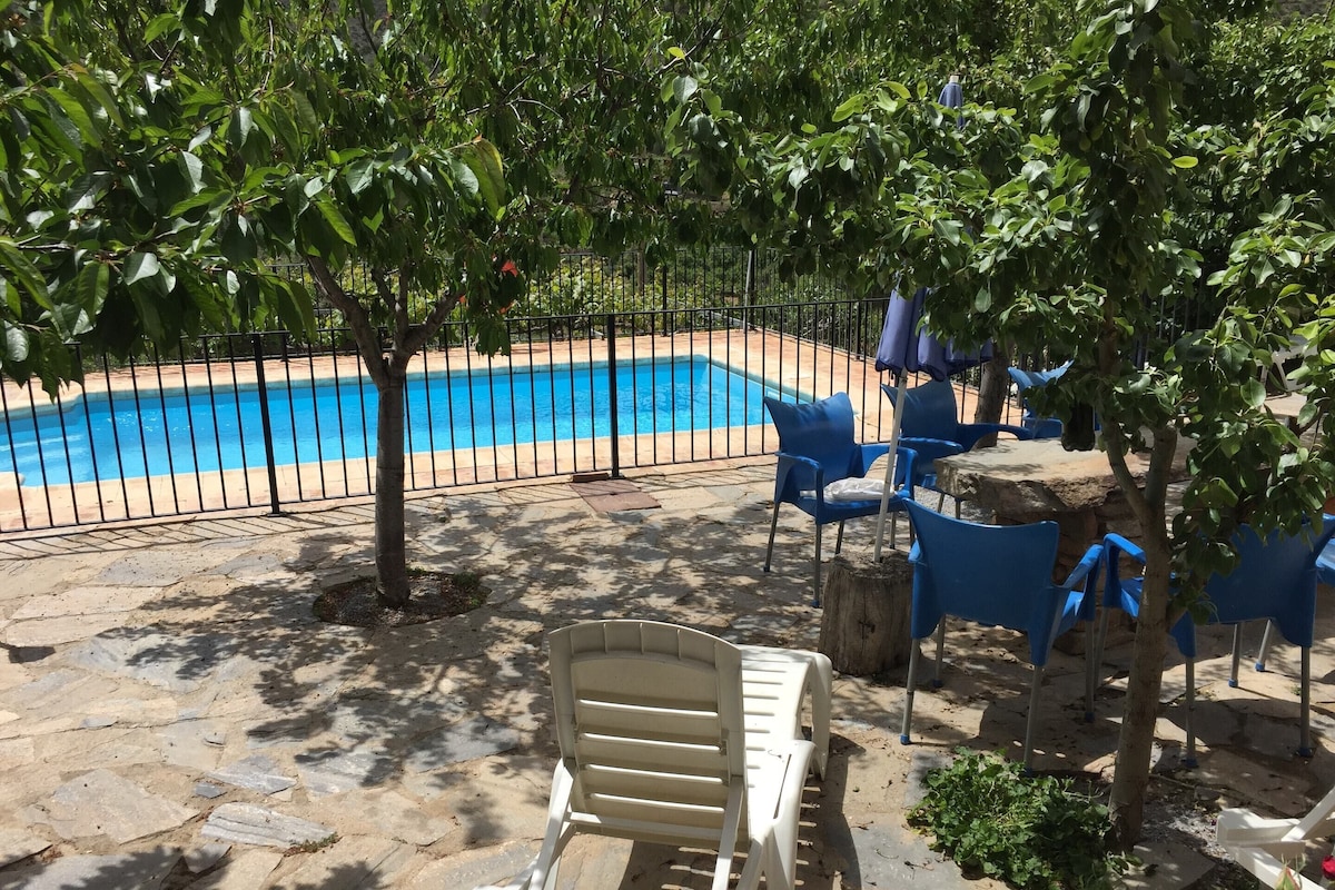 A pool area with a stone patio, blue chairs, and a white lounge chair.