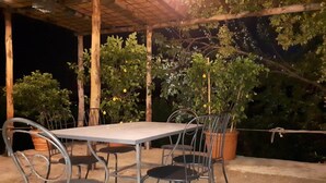 An outdoor patio with a table and chairs, surrounded by potted plants and a wooden pergola. - Simplistic Holiday Home in Pistoia With Terrace & Garden (Pistoia)