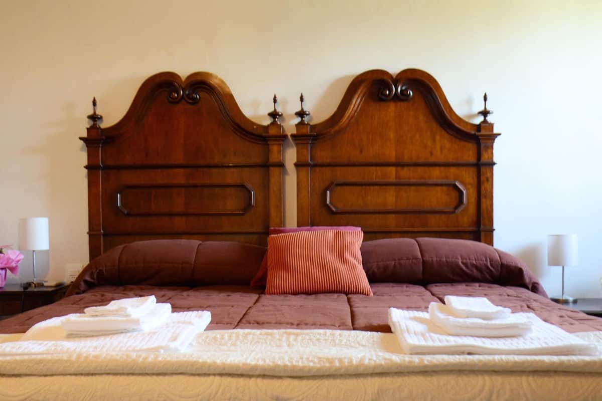 Un lit bien fait, avec une tête de lit en bois, deux oreillers et des serviettes pliées.