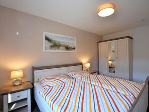 Ein Schlafzimmer mit einem Bett, zwei Nachttischen, einem Schrank und einem an der Wand hängenden Bild.