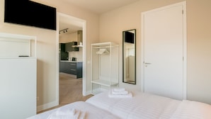 A hotel room with a bed, a wardrobe, a mirror, and a kitchenette in the background. - Apartment With sea View and Parking in Katwijk aan Zee (Katwijk Aan Zee)
