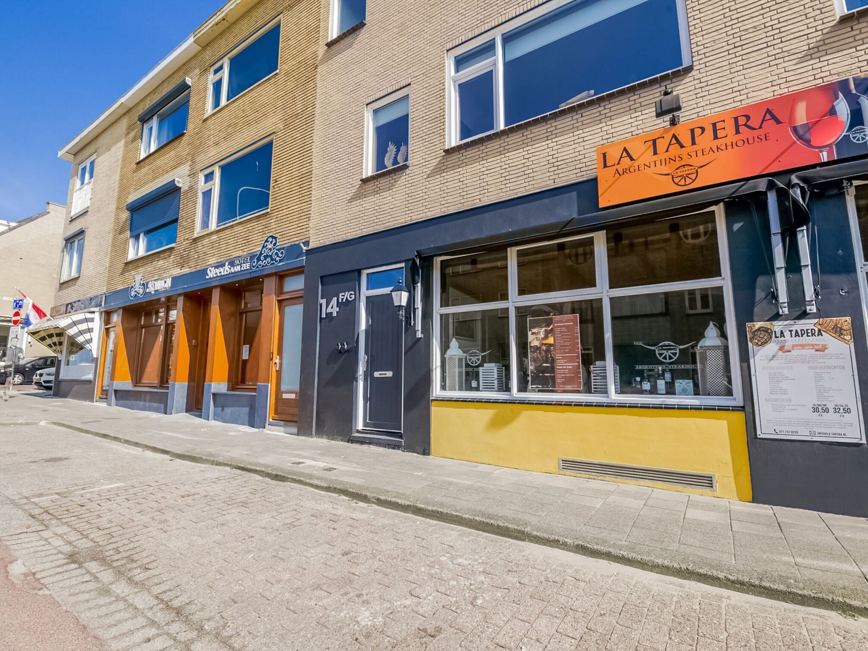 A hotel with a sign reading "Hotel Stadsman Zee" and a restaurant named "La Tapa Argentina Steakhouse" on the street.