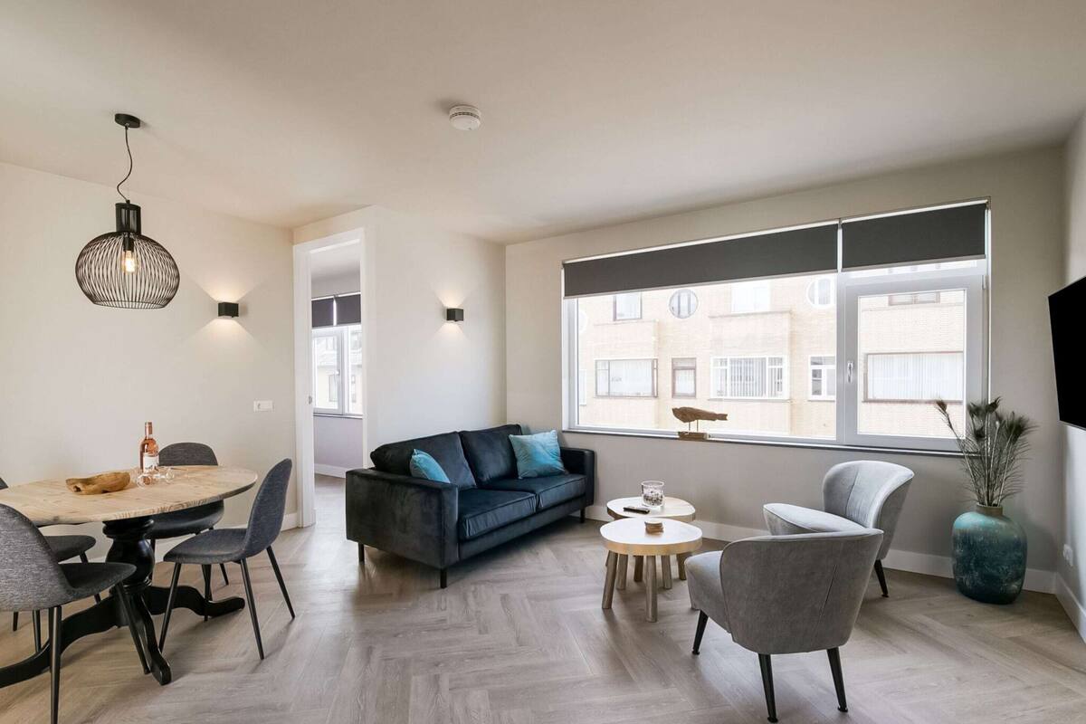 Un salon moderne comprenant un coin repas, un canapé et un téléviseur fixé au mur.