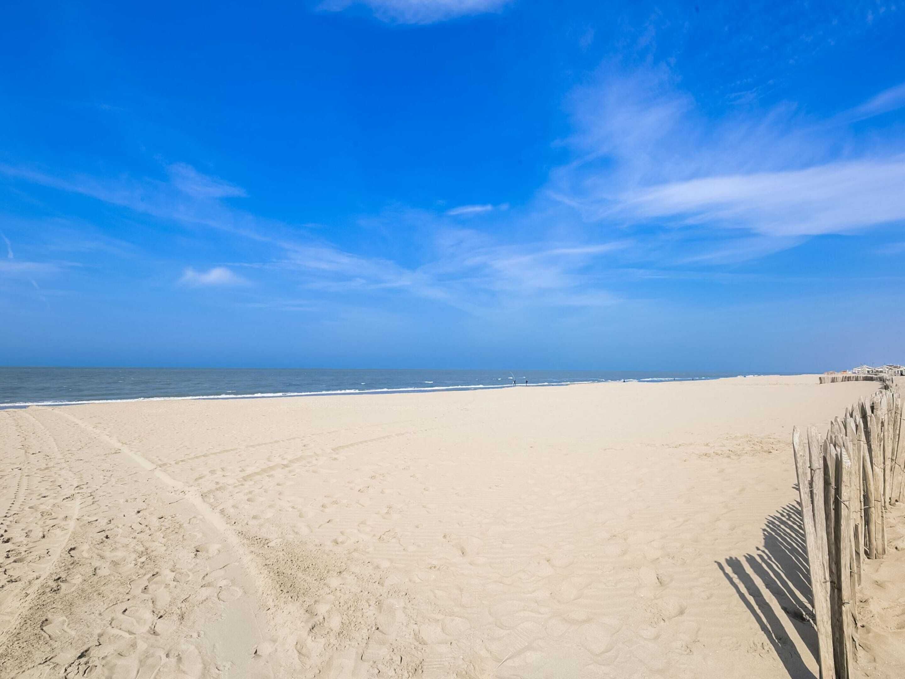 A beach with a wooden fence and a clear blue sky.